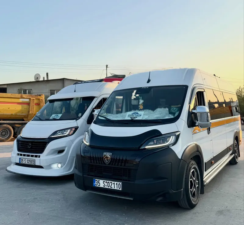 Gün batımında iki Özgür Turizm minibüsü